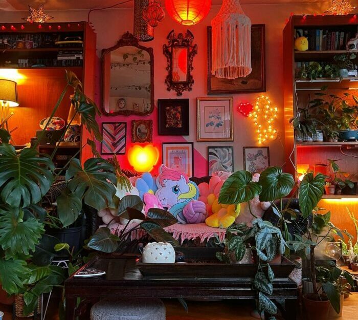 a maximalist living room lit with orange and yellow lighting and a sofa among many plants