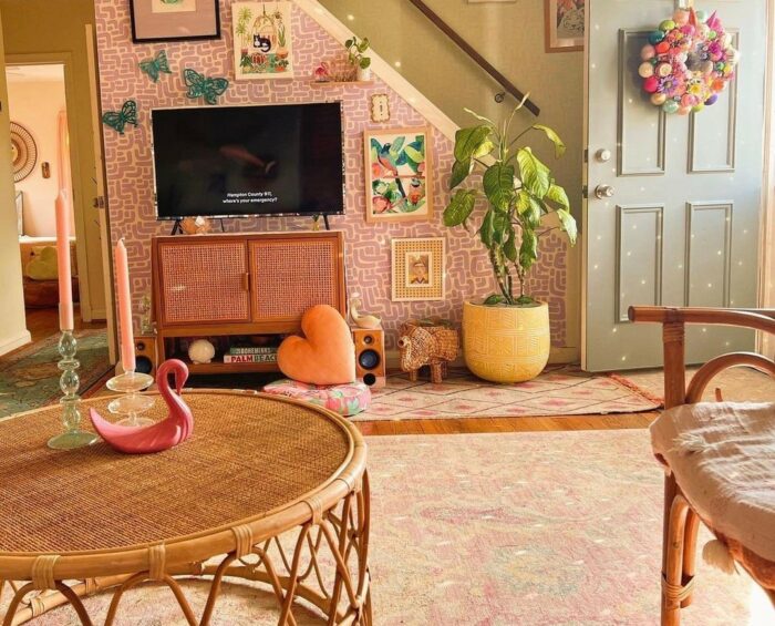 a peach maximalist living room with wicker furniture, plush pillows, and a plant