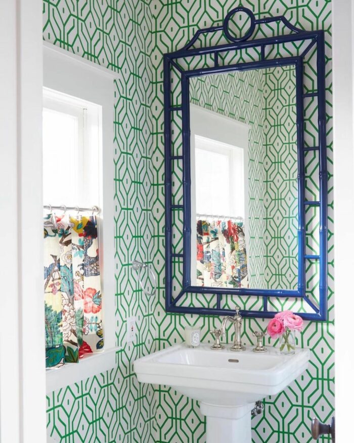 Bathroom with green tile patterned wallpaper with sink and mirror
