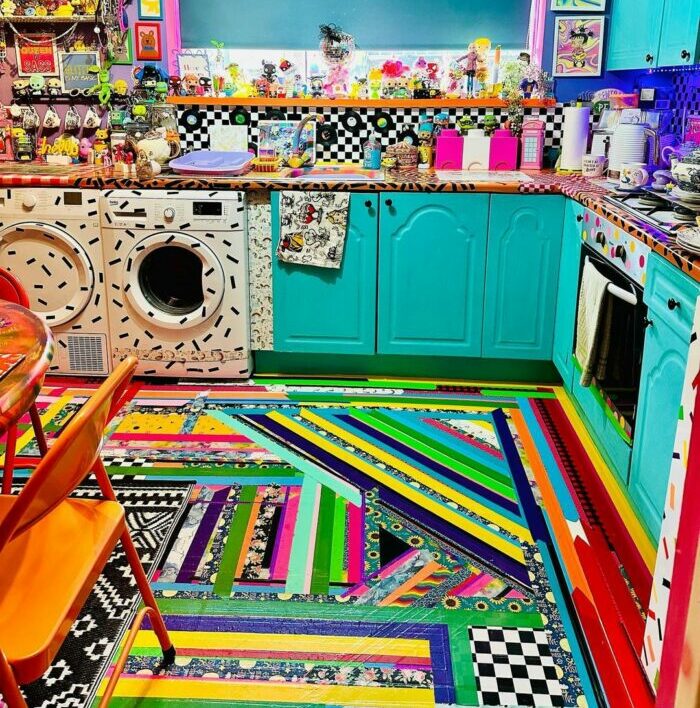 a colorful, maximalist kitchen with rugs, wall stickers, paintings, and many bright items