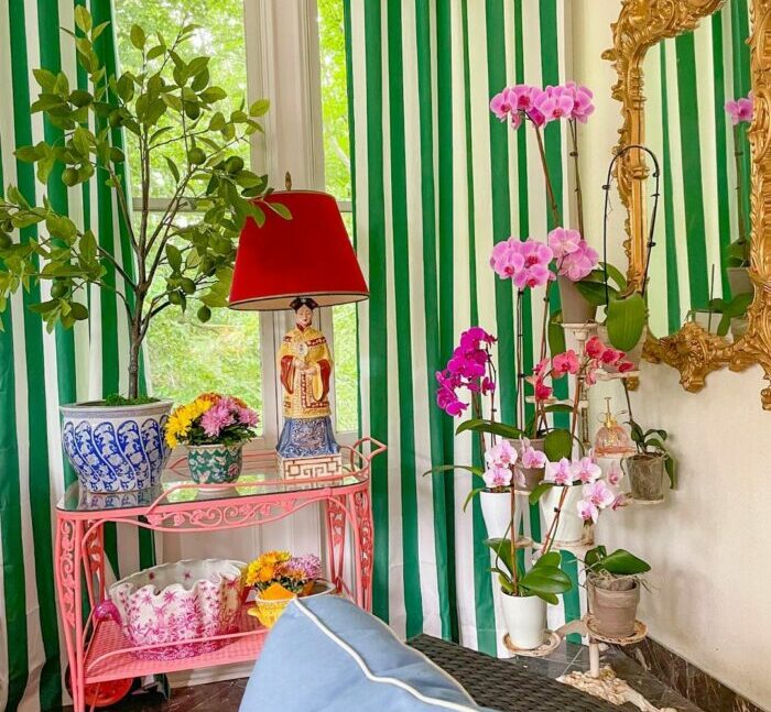 a maximalist living room with green and white stripe-patterned curtains