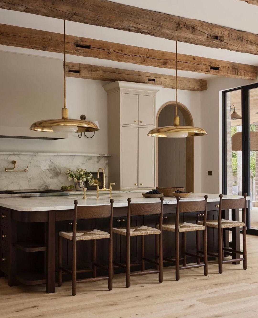 Kitchen with golden long pendants and marble wooden table with chairs