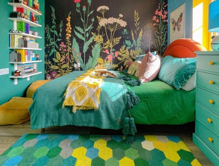 a maximalist bedroom with green-blue decor and dark tropical wallpaper