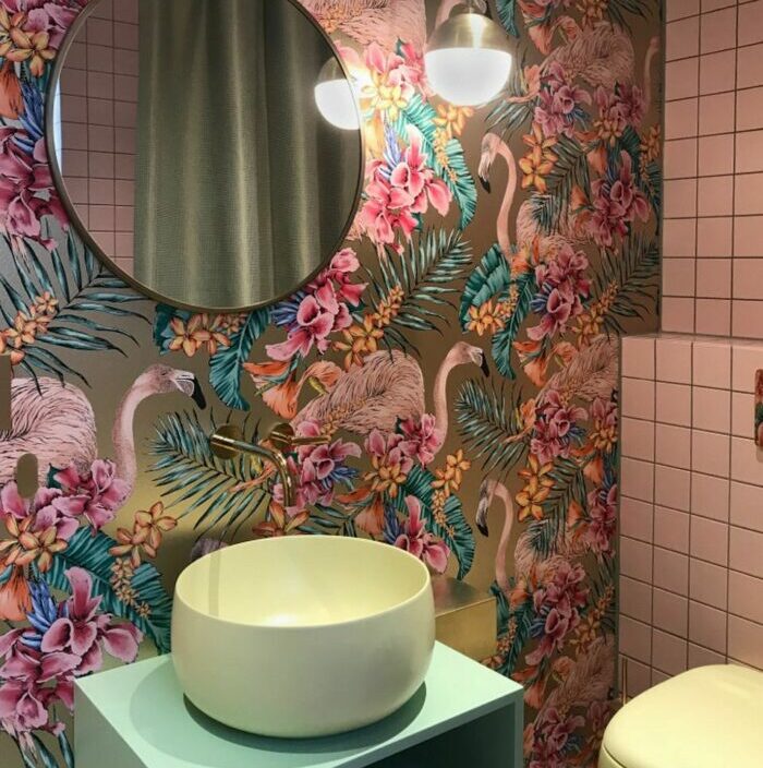 Bathroom with bright flower and flamingo wallpaper, round mirror, modern sink, and soft lighting fixtures. Bathroom with bright flower and flamingo wallpaper, round mirror, modern sink, and soft lighting fixtures.