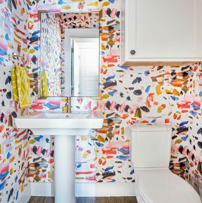 Bathroom with colorful paint swatch wallpaper with white sink and toilet