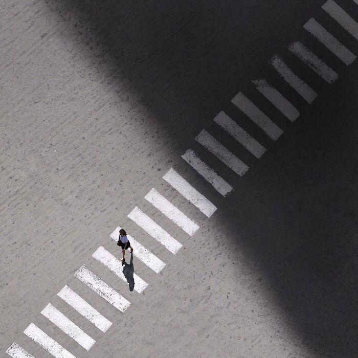 A photograph of a woman crossing the road