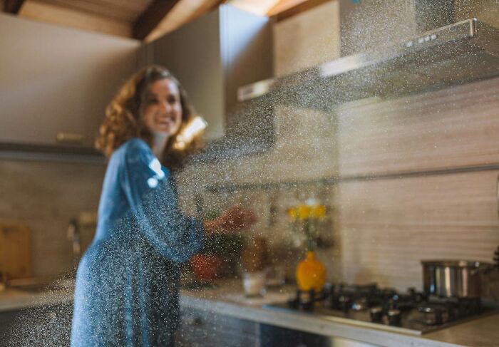 Woman in the kitchen and the beam of light with dust particles