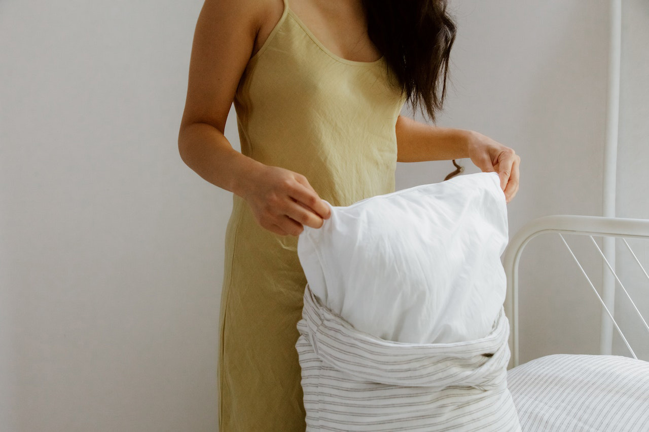 Woman with black hair changing light pillow case Woman with black hair changing light pillow case