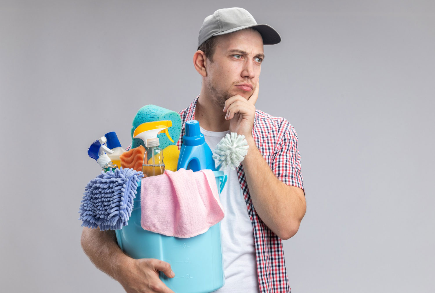 A young man is thinking and holding a bucket with cleaning tools