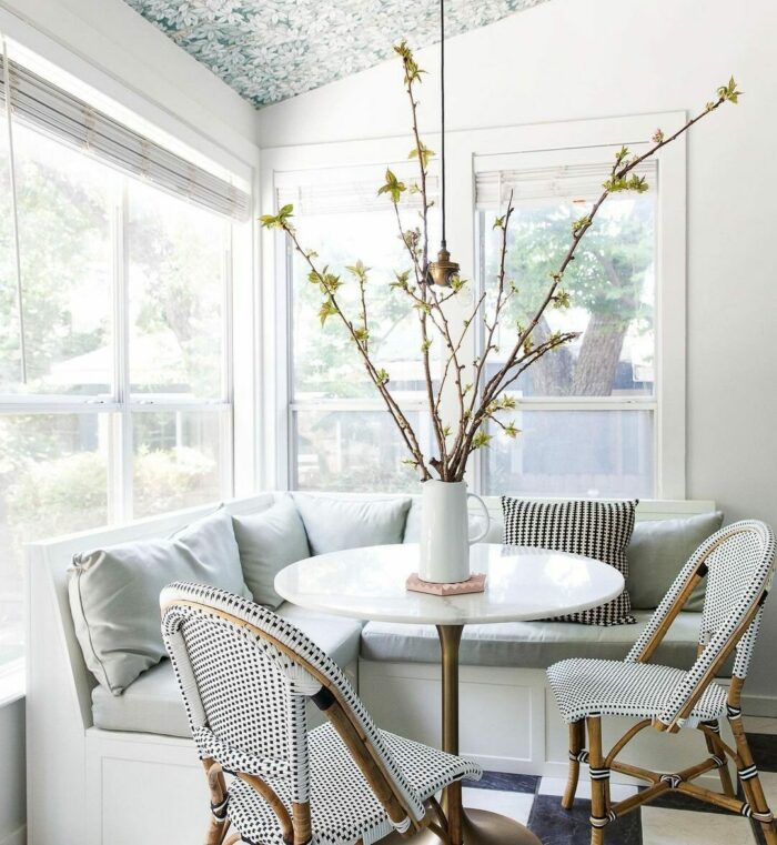 white banquette near window with gray pillows white table and chairs