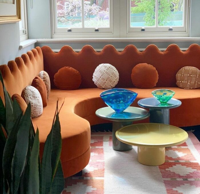 Curvy orange banquette with pillows and small tables