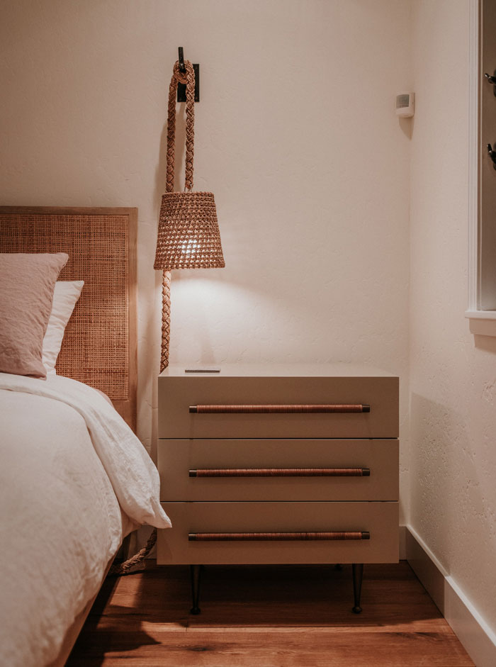 A bedroom with a bed, nightstand and lamp