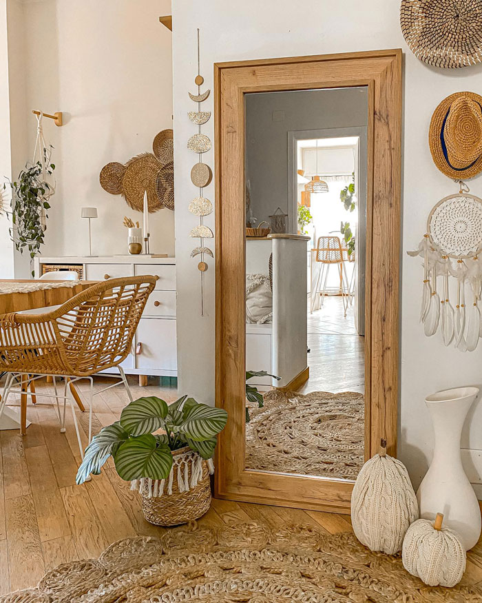 Huge wooden mirror on the wall and plants on the floor 