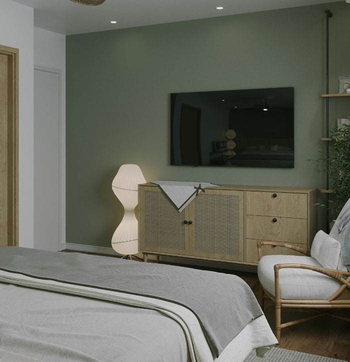 A green bedroom with TV on the wall and wooden low cabinet