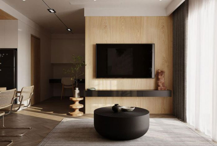 A TV hanging on the wall, dark brown coffee table in the centre of the room 
