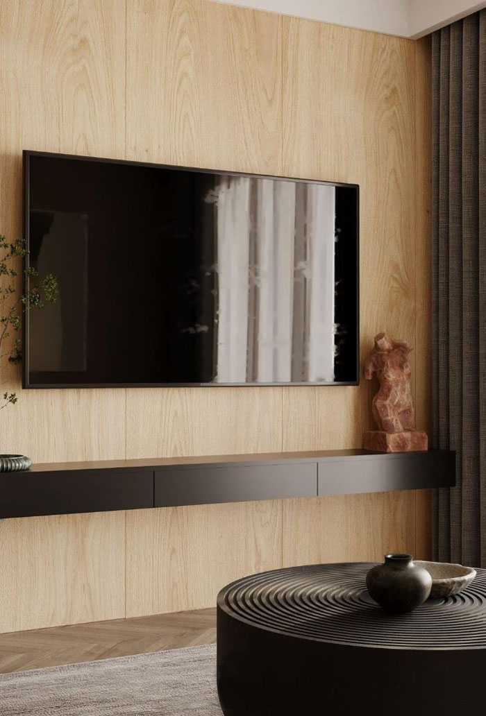 A TV hanging on the wall, dark brown shelf with statue and plant 