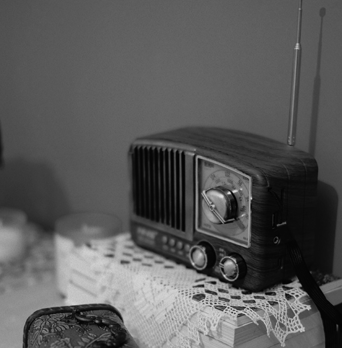 Vintage wooden radio with knobs and antenna on a lace-covered surface, evoking scary facts atmosphere.