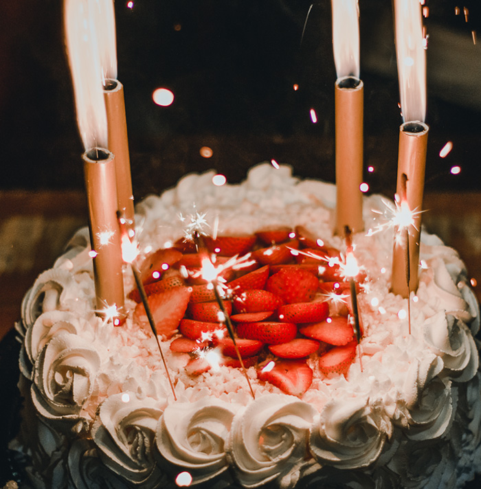 Close-up of a cake with strawberries and sparklers creating scary facts-themed heebie-jeebies visual effect at night.