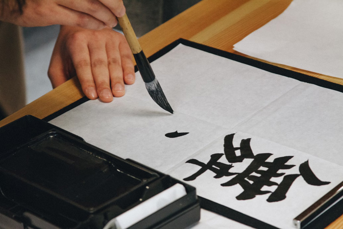 Person writing in Japanese writing format kanji
