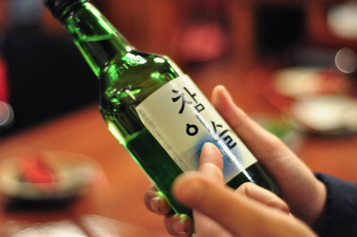 A person holding a bottle of Soju 