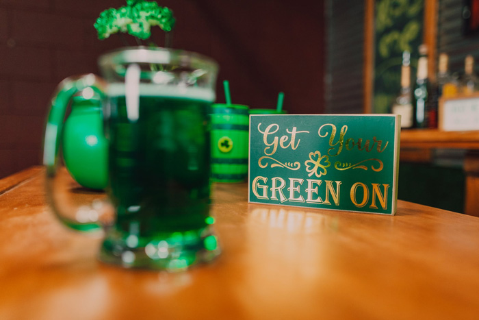 Clear glass mug with green liquid in it next to a table with 'Get Your Green On' script on it