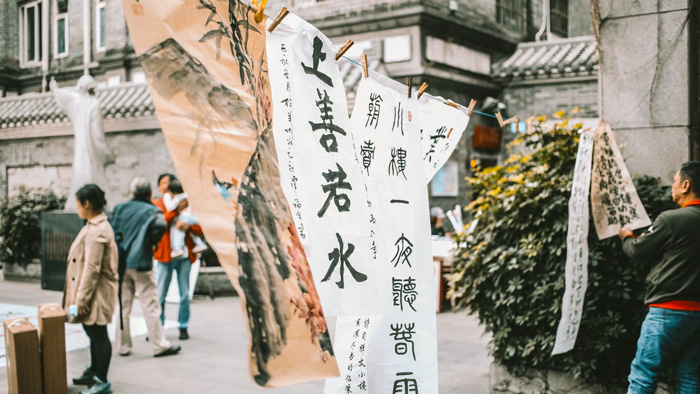 Hanging sheets of paper outside with calligraphy text written on them