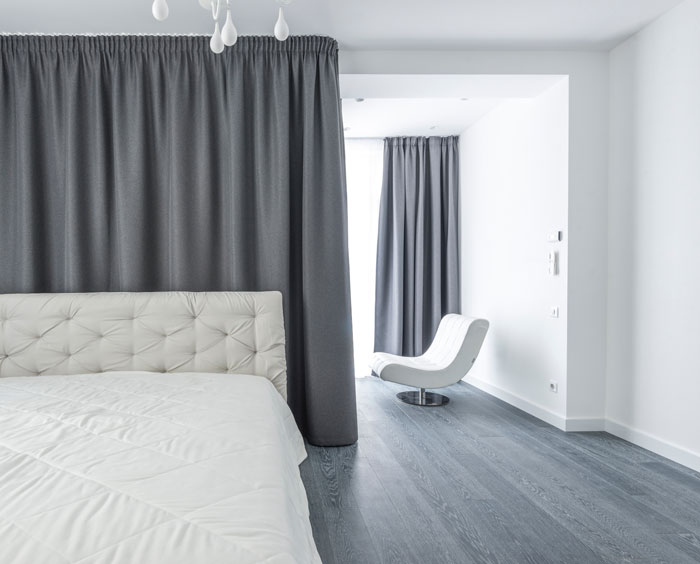 a cozy white bed near the grey curtains a cozy white bed near the grey curtains