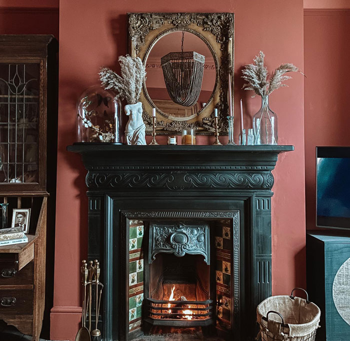 Powder pink living room with a black fireplace and a vintage gilded frame mirror
