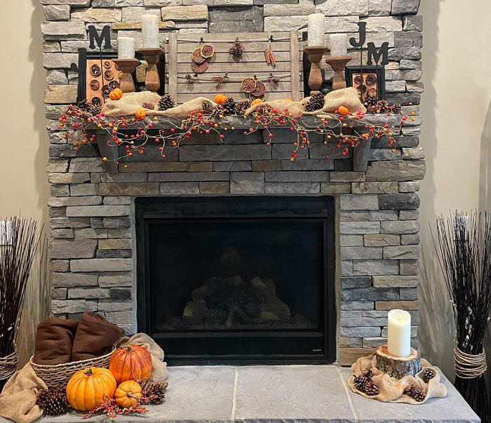 Stone fireplace mantel decorated with pumpkins, pinecones, candles, and autumn berries for a Halloween-themed hearth. Stone fireplace mantel decorated with pumpkins, pinecones, candles, and autumn berries for a Halloween-themed hearth.