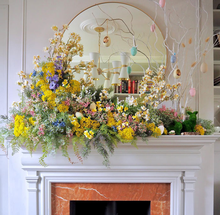White fireplace with red marble detailing and bright colorful flowers on the mantle 