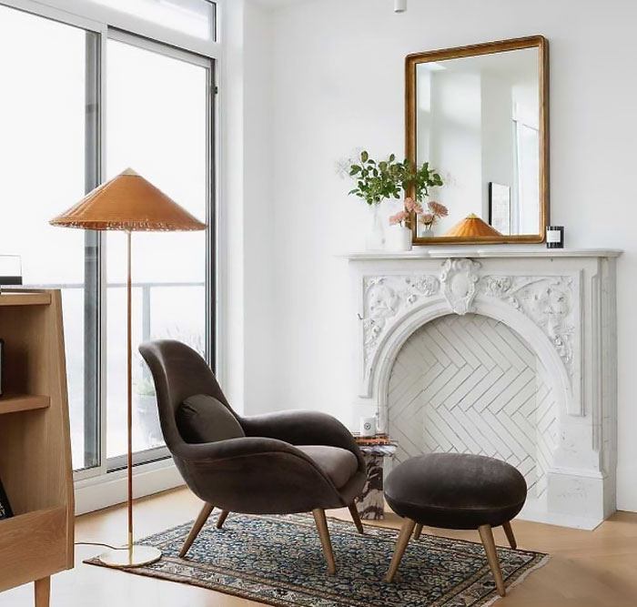 Ornate Victorian white arch fireplace mantel with floral carvings in a bright living room featuring modern furniture. Ornate Victorian white arch fireplace mantel with floral carvings in a bright living room featuring modern furniture.