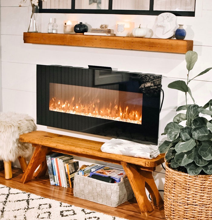 Black electric fireplace with wooden mantel in a light boho living room featuring cozy decor and greenery accents Black electric fireplace with wooden mantel in a light boho living room featuring cozy decor and greenery accents
