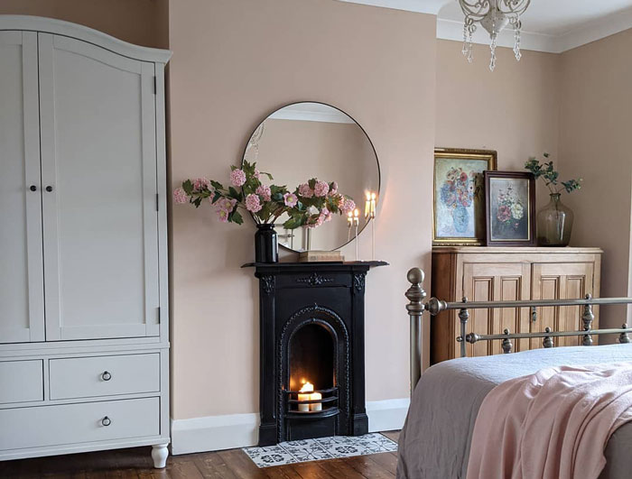 Farmhouse bedroom with a black fireplace mantel featuring upcycled detailing and fresh flowers in a cozy setting. Farmhouse bedroom with a black fireplace mantel featuring upcycled detailing and fresh flowers in a cozy setting.