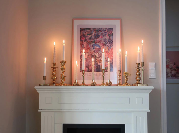 White wooden fireplace mantel decorated with multiple antique candle holders, creating a cozy hearth ambiance. White wooden fireplace mantel decorated with multiple antique candle holders, creating a cozy hearth ambiance.