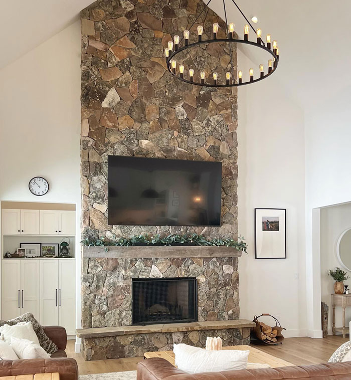 Stone backsplash fireplace mantel with mounted TV above, featuring rustic living room design and cozy hearth decor. Stone backsplash fireplace mantel with mounted TV above, featuring rustic living room design and cozy hearth decor.
