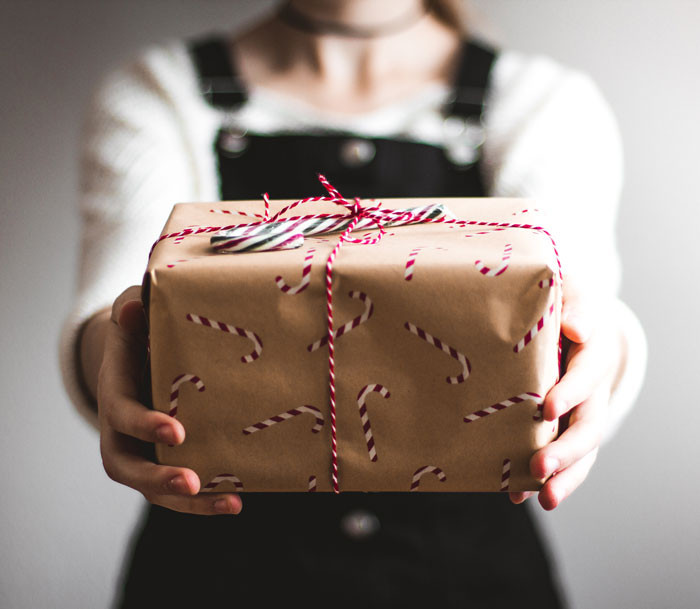 Woman holding gift in wrapping paper and ribbon 
