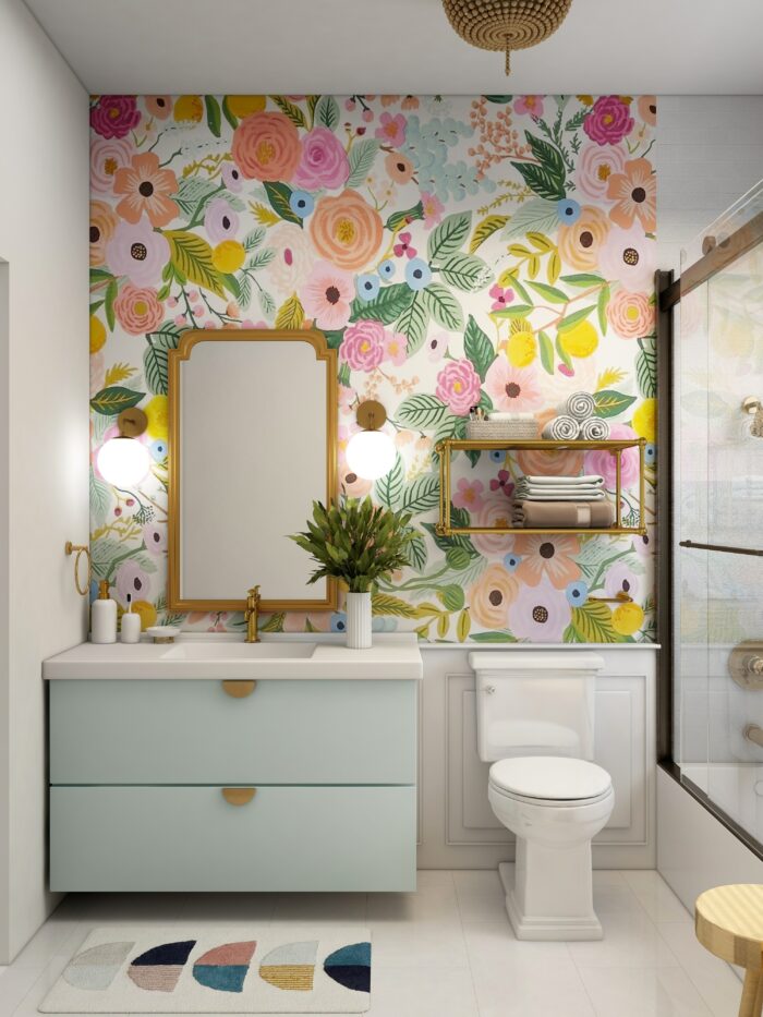 Bathroom with flower wallpaper and a sink with blue cabinets and toilet