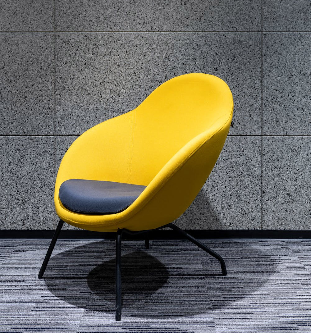 Yellow armchair with cushion at wall