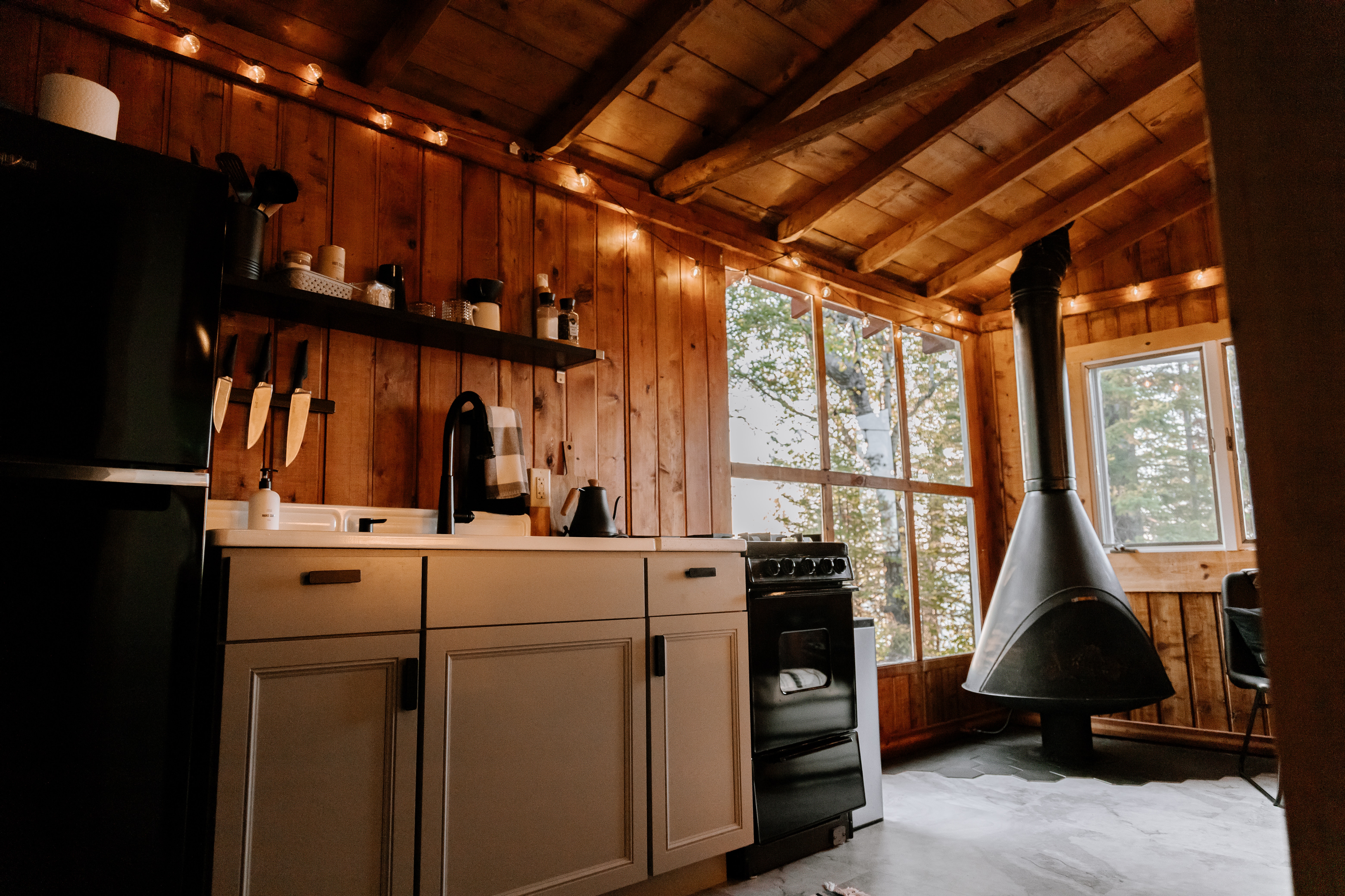 A wooden kitchen with a stove top oven next to a window and cove lighting
