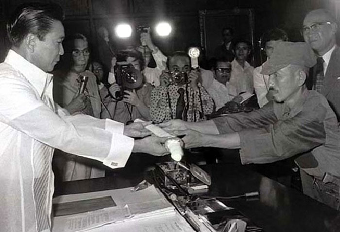 Hiroo Onoda (right) offers his military sword to Philippine President Ferdinand Marcos (left) on the day of his surrender, 11 March 1974