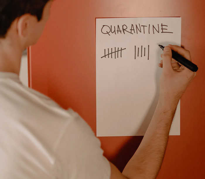 Man in white T-shirt counting quarantine days on paper