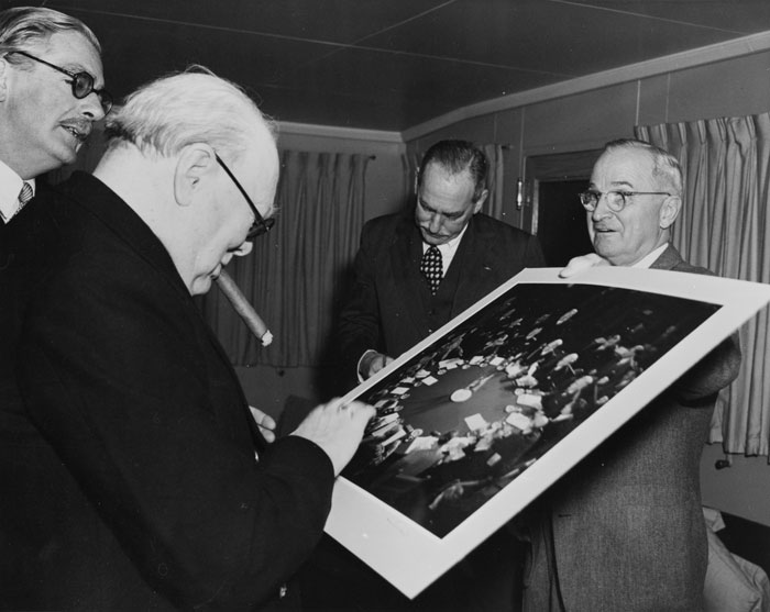 Photograph of President Truman giving Winston Churchill, who is smoking a cigar, a picture from the 1945 Potsdam Conference
