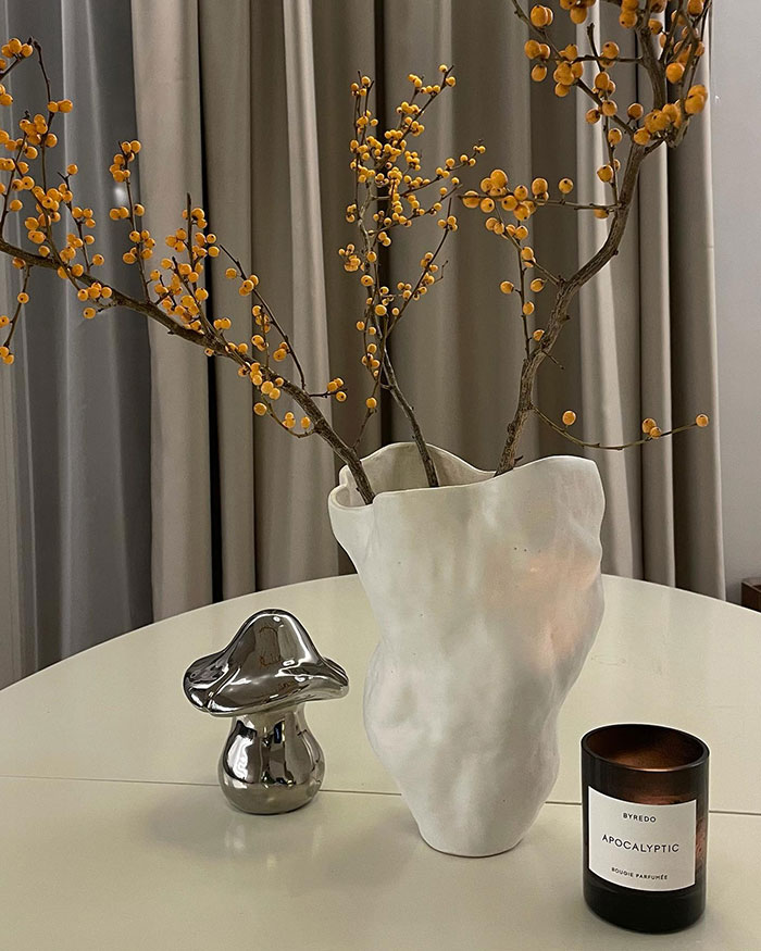 Handmade white vase with branches on table beside metallic mushroom and scented candle, showcasing home decor ideas and nowness. Handmade white vase with branches on table beside metallic mushroom and scented candle, showcasing home decor ideas and nowness.