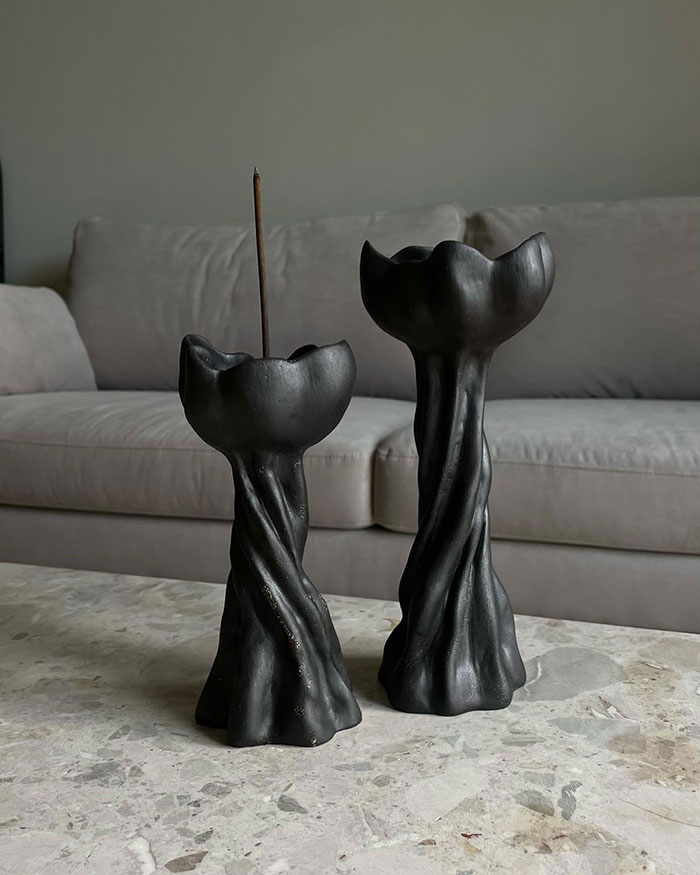 Two black sculptural candleholders on a marble table in a grey room showcasing unique home decor ideas. Two black sculptural candleholders on a marble table in a grey room showcasing unique home decor ideas.