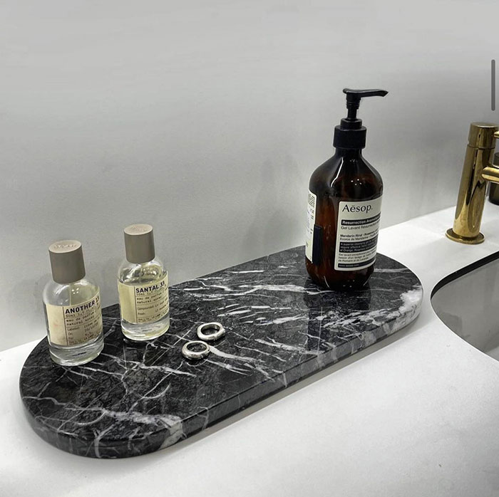 Cosmetics and jewellery arranged on a sleek black marble tray in a bathroom, showcasing modern home decor ideas. Cosmetics and jewellery arranged on a sleek black marble tray in a bathroom, showcasing modern home decor ideas.