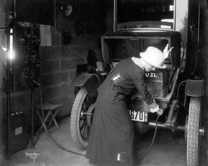 Mujer cargando su coche eléctrico en su garaje, 1912