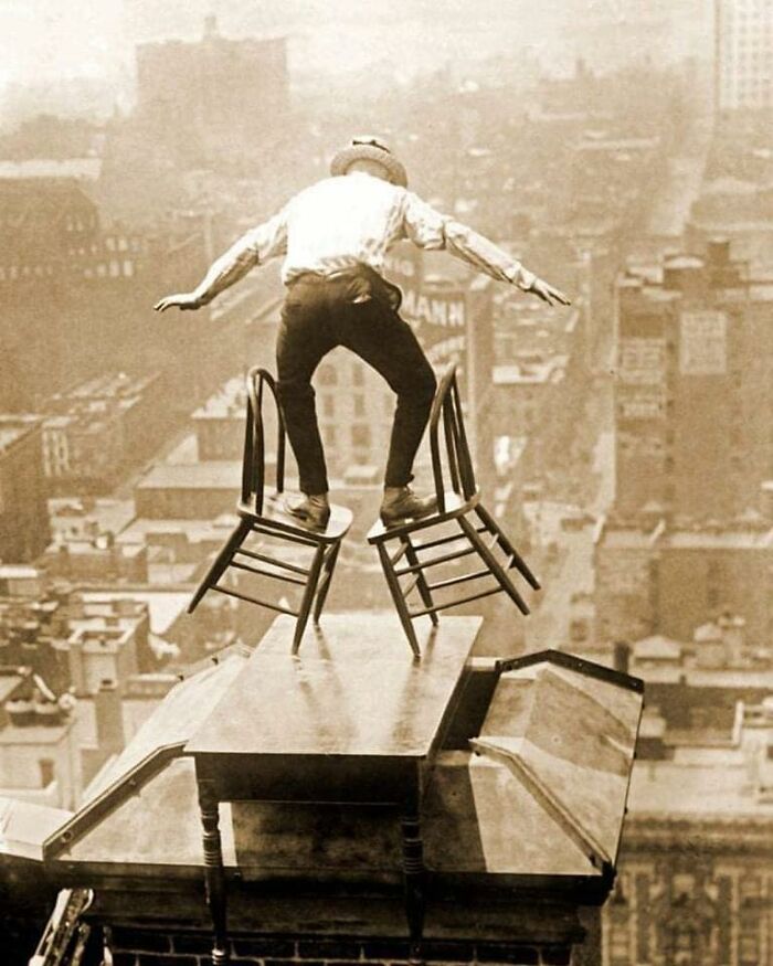 A Daredevil Balances On The Roof Edge Of A Manhattan Building, Perched On A Table Placed Over A Chimney, 1910s