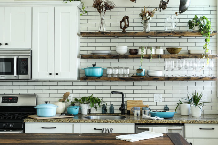 open shelving kitchen with long wooden shelves and white bricks wall