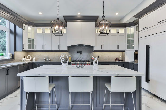 white marble and gray kitchen cabinets with white bar chairs