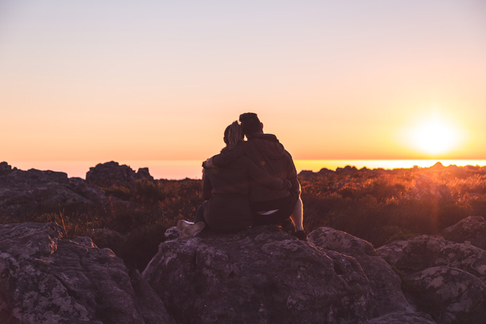 Couple on top of rocks watching a sunset
